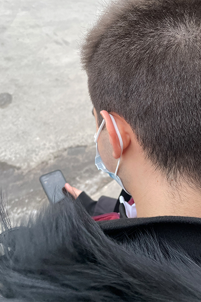 Dennis scrolling through his phone outside.