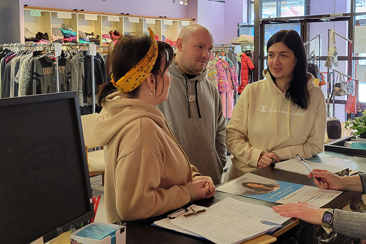 Husband and wife speak with the donations coordinator by a desk.