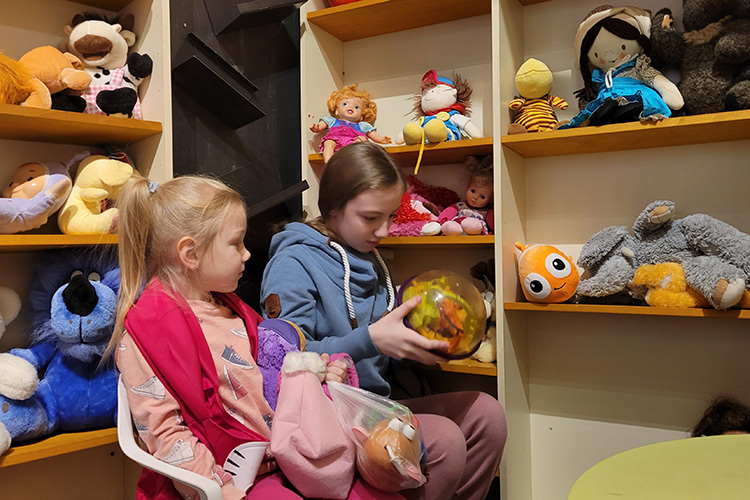 Two girls play with toys in the children's section of the centre.