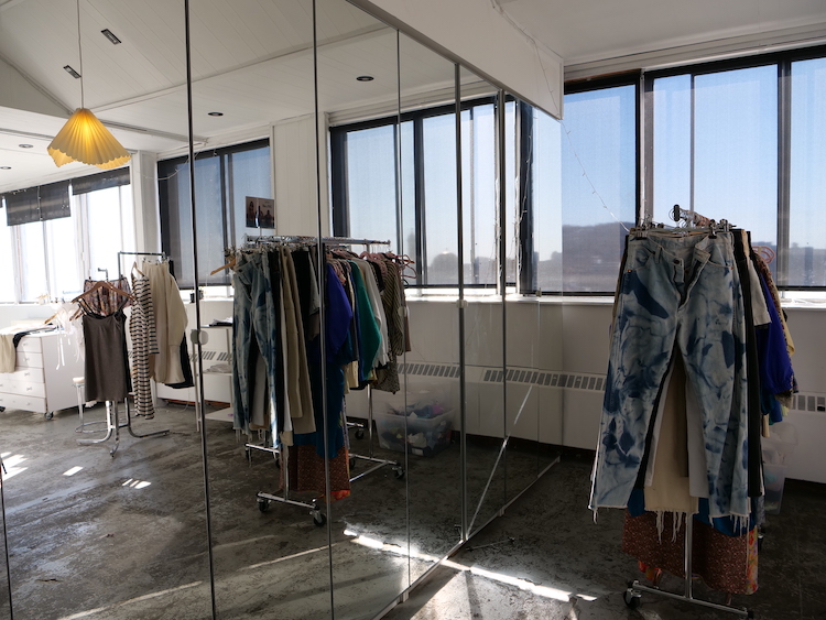 A clothing rack in front of a mirror.