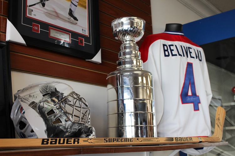 A collection of Jean Beliveau’s signed hockey stick, jersey, Stanley Cup, and helmet.