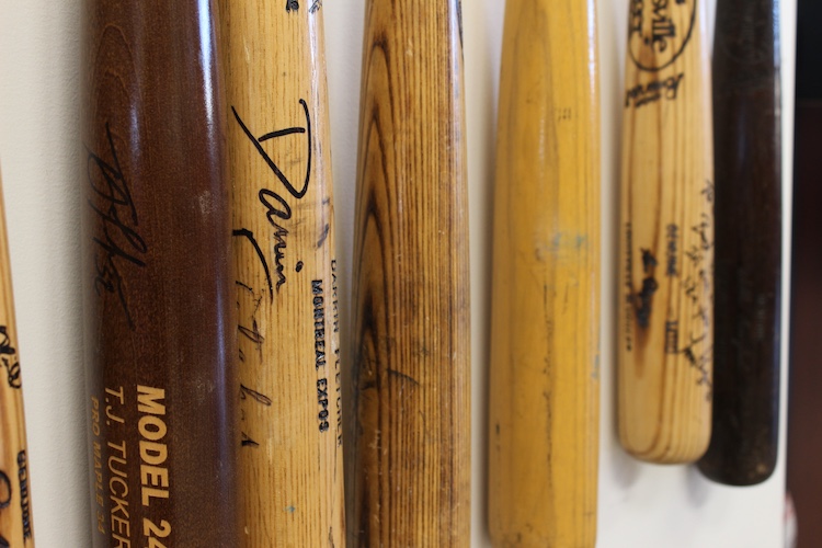 A collection of signed baseball bats from professional players at the KSKS Sports Collectibles store.