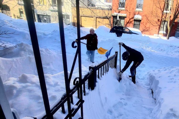 Two boys shovelling heaps of snow outside of Guy Glorieux's home