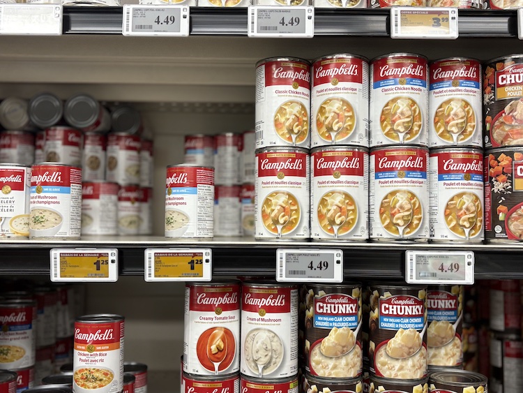 A grocery store shelf with soup cans. 