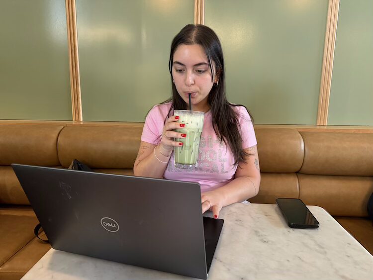 Mathilde Choquette sits at a table in a coffee shop, working on her laptop while sipping a matcha drink which she prefers as a healthier alternative to coffee.